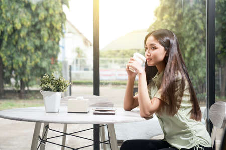 Asian woman holding coffee in the coffee shopの写真素材