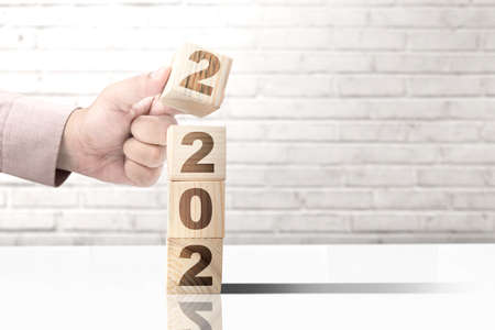 Hand put the 2022 on the stack of the wooden cube. Happy New Year 2022