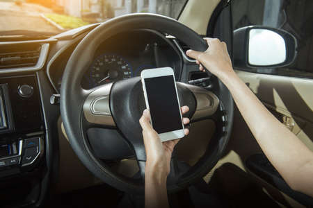 Woman hand holding a mobile phone in the car