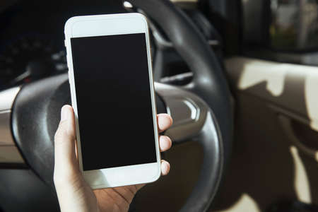 Woman hand holding a mobile phone in the carの写真素材
