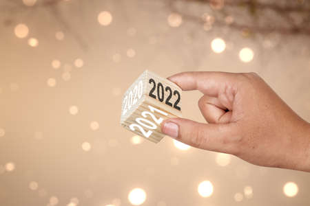 Human hand showing 2022 side on the wooden cube. Happy New Year 2022