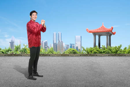An Asian Chinese man in a cheongsam dress with a congratulations gesture. Happy Chinese New Yearの写真素材