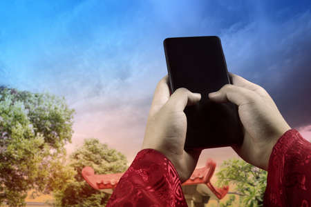 Hand holding mobile phone with a dramatic sky background. Happy Chinese New Year