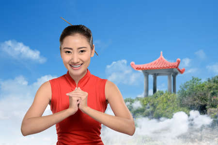Asian Chinese woman in a cheongsam dress with congratulations gesture. Happy Chinese New Yearの写真素材