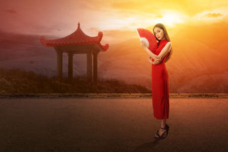 Asian Chinese woman in a cheongsam dress holding fan celebrates Chinese New Year. Happy Chinese New Yearの写真素材