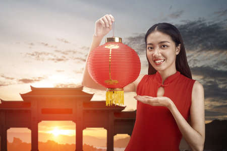 Asian Chinese woman in a cheongsam dress holding Chinese lantern. Happy Chinese New Yearの写真素材