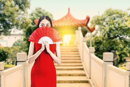 Asian Chinese woman in a cheongsam dress holding fan celebrates Chinese New Year. Happy Chinese New Yearの写真素材