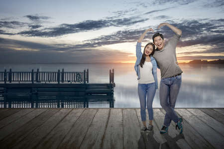 Asian couples make the shape of a heart with hands with a dramatic sky background. Valentines dayの写真素材