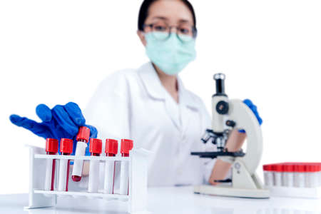Asian researcher woman with face mask and glasses taking the medical tube from rack isolated over white backgroundの写真素材