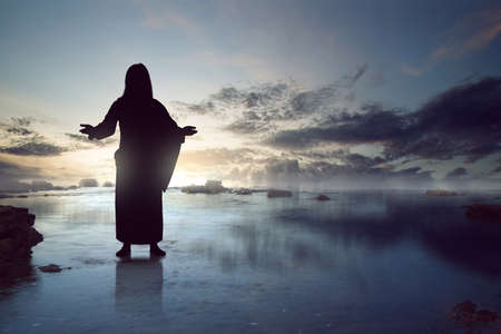Silhouette of Jesus Christ standing on the water with dramatic backgroundの写真素材