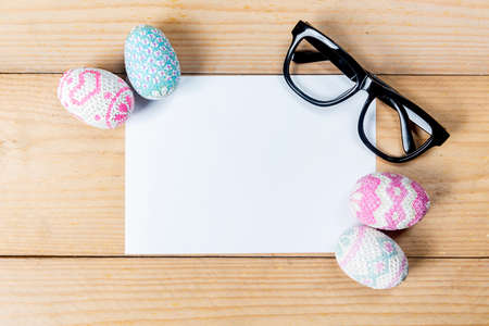 Colorful easter egg with empty paper on a wooden table. Happy Easterの写真素材
