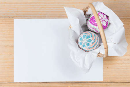 Colorful easter egg on the basket with empty paper on a wooden table. Happy Easterの写真素材