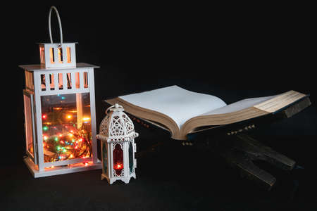 Quran open on a wooden placemat with Arabic lamp on dark background