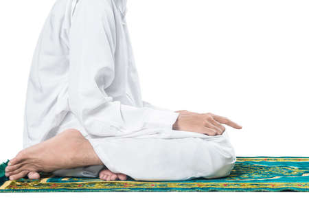 Close up view of Muslim man in a praying position (salat) on a prayer rug isolated over white backgroundの写真素材