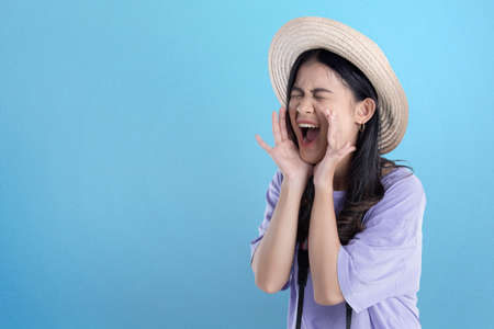 Asian woman with hat and camera yelling something with colored backgroundの写真素材