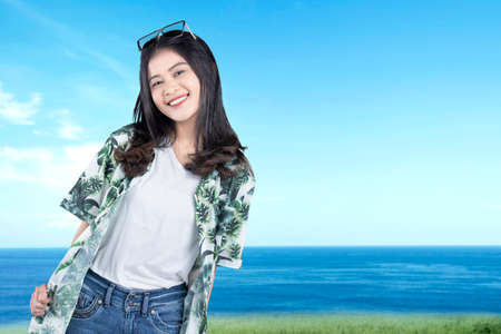 Asian woman with sunglasses standing with colored backgroundの写真素材