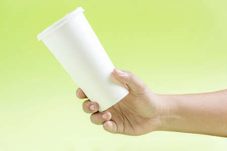Human hand holding a white plastic cup with colored background