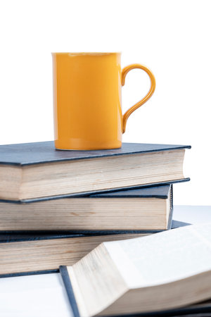 Closeup view of the stack of books with a mug on the deskの写真素材