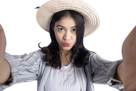 Asian woman with a hat taking a self-portrait isolated over white backgroundの写真素材