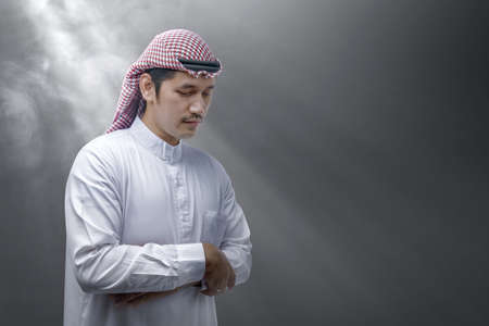 Muslim man with keffiyeh with agal in praying position (salat) with light backgroundの写真素材