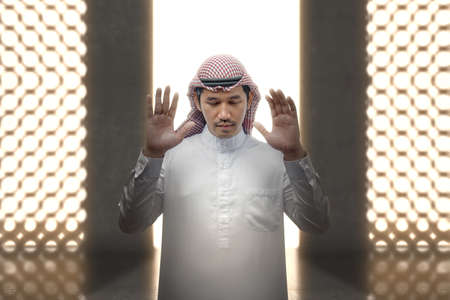 Muslim man with keffiyeh with agal in praying position (salat) inside the mosque