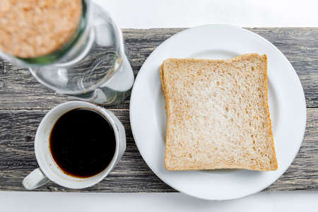Sliced bread and a cup of coffee on the board isolated over white backgroundの写真素材