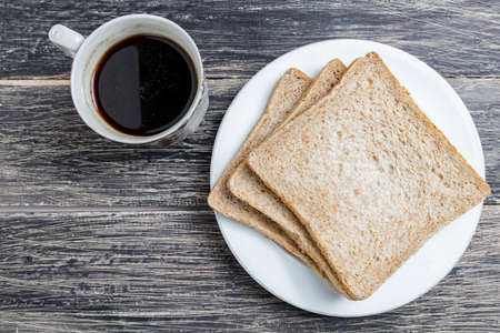 Sliced bread on the plate and a cup of coffee on the wooden backgroundの写真素材