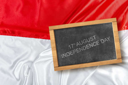 Small chalkboard with Indonesian independence day message with a red and white flag background....