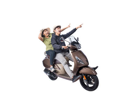 An Asian couple with a hat is sitting on a scooter and pointing something isolated over white backgroundの写真素材