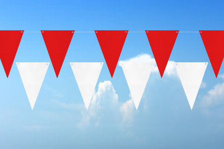 Indonesian flag hanging with ropes with blue sky backgroundの写真素材