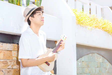 Asian man with hat playing guitar ukulele at outdoorの写真素材