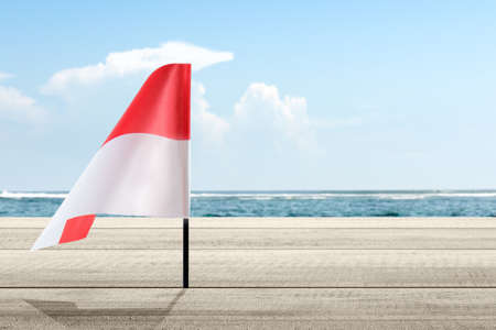 Indonesian flag on a sandy beach with a blue sky background. Indonesian independence day