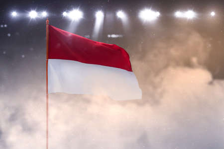 Indonesian flag on the pole waving with spotlights backgroundの写真素材