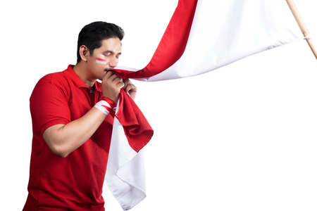 Indonesian men celebrate Indonesian independence day on 17 August by kissing the Indonesian flag isolated over white backgroundの写真素材