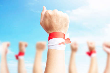 Human hands show ribbon with the red and white color of the Indonesian flag with a blue sky background. Indonesian independence dayの写真素材