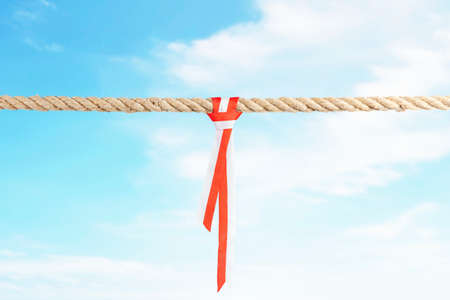 Ribbon with the red and white color of the Indonesian flag on ropes string with a blue sky background. Indonesian independence dayの写真素材