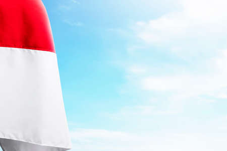 The red and white flag of Indonesian flag with blue sky backgroundの写真素材