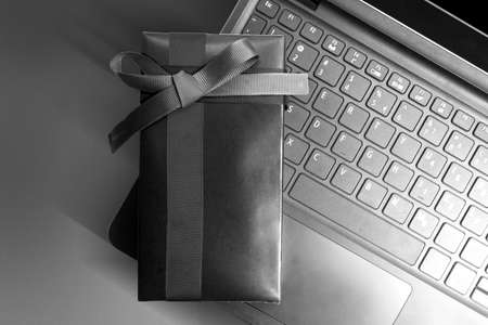Black gift box with black ribbon on a laptop with a colored background. Black Friday conceptの写真素材