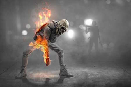 Man with a skull head costume on fire with a dark background. Halloween concept