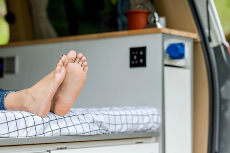 Woman lying down inside the campervan enjoying camp activity in natureの写真素材