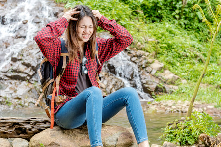 Asian woman with backpack feeling headache while walking in the forestの写真素材