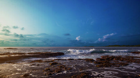 Sandy beach with the blue ocean and blue sky background