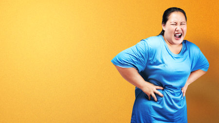 Asian fat overweight woman feeling stomach ache with colored backgroundの写真素材