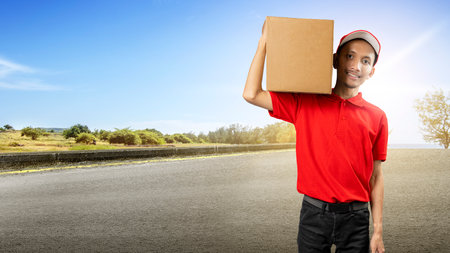 Parcel delivery man with a hat carrying a package in the city