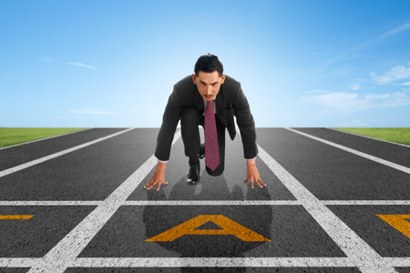 Asian businessman in start position ready to run on the streetの写真素材