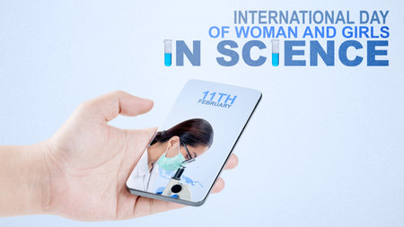 Human hands holding mobile phones with a screen of Asian scientists using microscopes with a colored background. International Day of Women and Girls in Scienceの写真素材