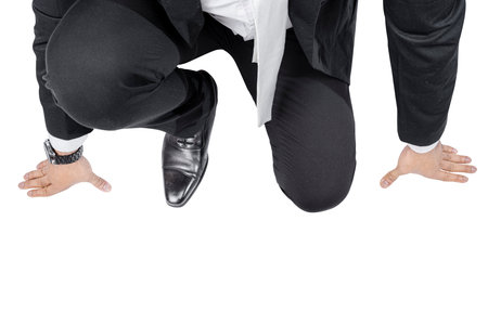 Businessman in start position ready to run isolated over white backgroundの写真素材