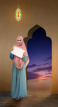Asian Muslim woman in veil holding empty paper in the mosque. Empty paper for copy spaceの写真素材
