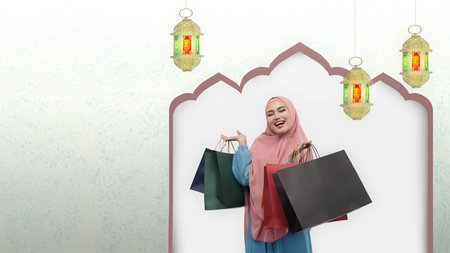Asian Muslim woman in veil holding shopping bags with hanging Arabic lamp background