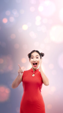 Asian Chinese woman in a cheongsam dress pointing to something. Happy Chinese New Yearの写真素材